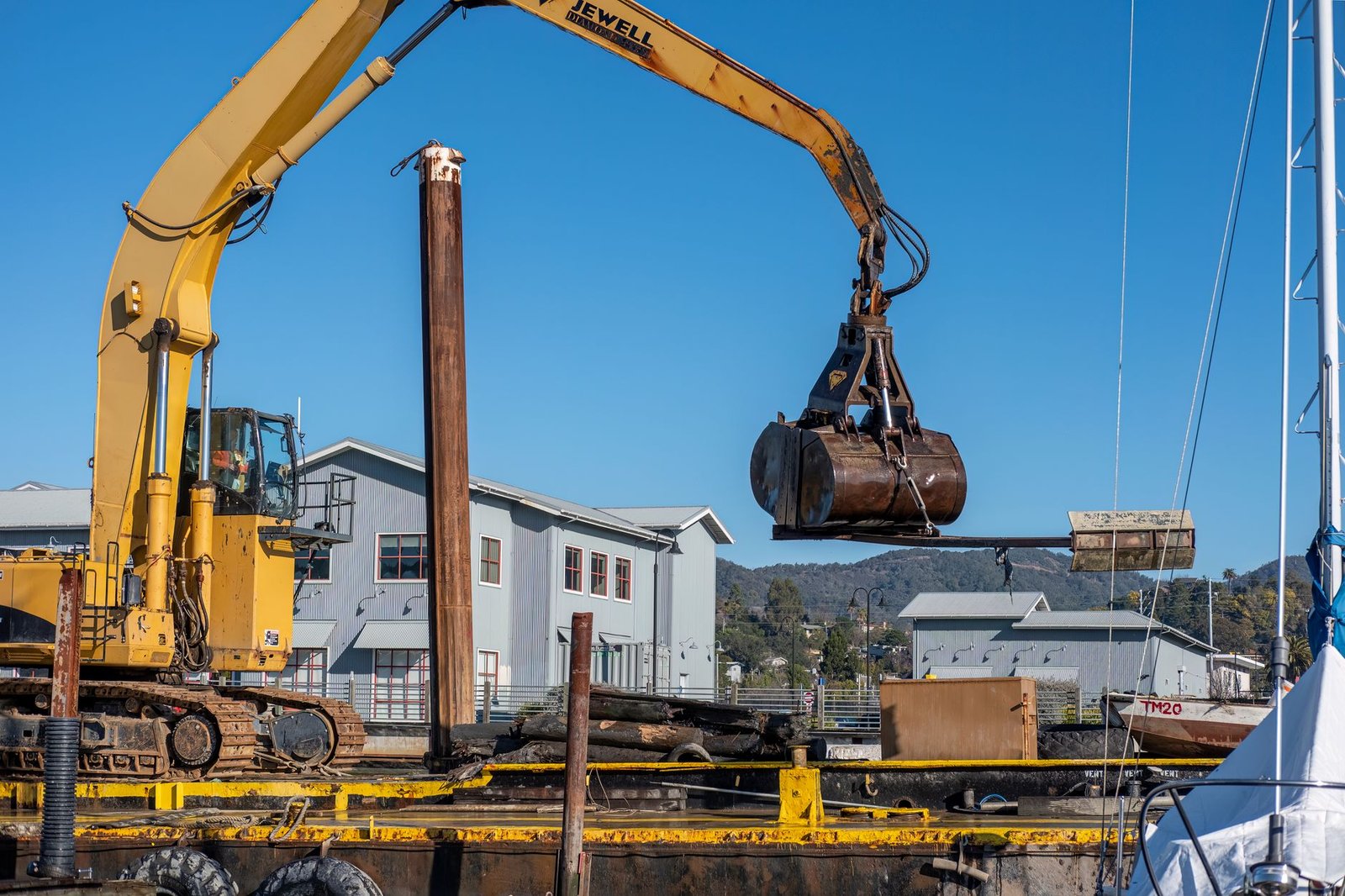 Crane lifting a large cut tree section up and over a yard during a removal job